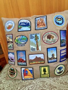 a pillow with many different stickers on it sitting on a bed next to a wooden headboard