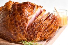 sliced ham on a cutting board next to a glass of orange juice and some herbs