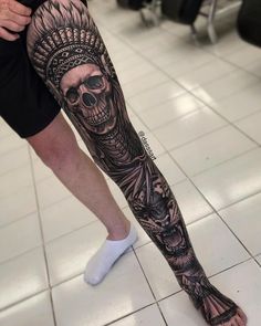 a man's leg with a skeleton and headdress tattoo on the legs