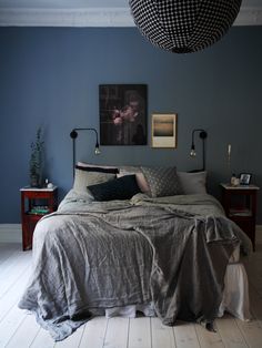 a bed sitting in a bedroom next to a lamp and pictures on the wall above it