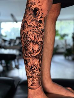 a man's leg with a tiger tattoo on it and flowers around the ankles