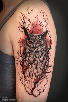 an owl with horns and branches on the back of a woman's upper arm