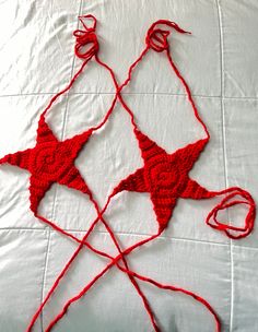 two red crocheted stars sitting on top of a white bed next to each other