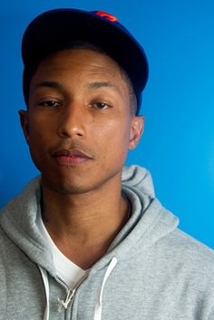 a young man in a grey hoodie is posing for the camera with a blue background