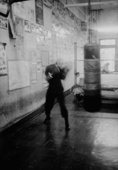 black and white photograph of a man in a boxing ring with punching bag behind him