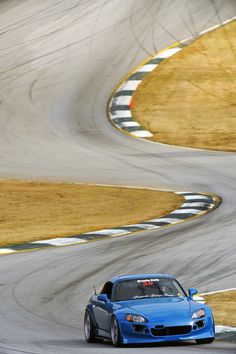 a blue sports car driving on a race track