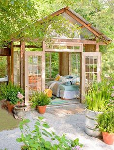 an image of a small garden shed with lots of plants and flowers in the yard