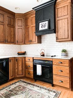 a kitchen with wooden cabinets and black appliances in the corner, including an area rug on the floor