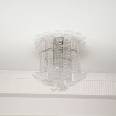 a glass chandelier hanging from the ceiling in a room with white walls and ceilings