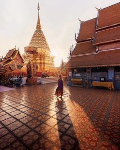 a woman walking across a tiled floor in front of a tall building with many spires