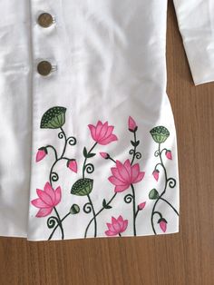 a white shirt with pink flowers and green leaves on the front, sitting on a wooden surface