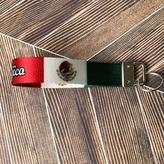 a keychain with the flag of mexico on it sitting on a wooden floor