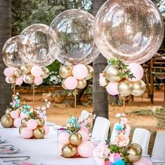 balloons and flowers are on the table for an outdoor wedding reception with pink, gold and blue decorations