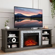 a flat screen tv sitting on top of a wooden entertainment center next to a fire place