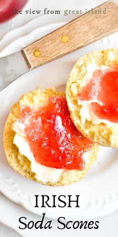 two scones with strawberry jam and whipped cream on them sitting on a white plate