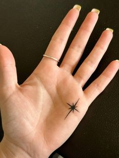 a person's hand with a small star tattoo on the middle of their palm