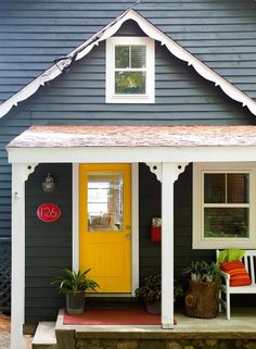 a yellow door sits in front of a gray house