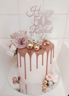 a pink and white cake with flowers on top is sitting on a table in front of a tiled wall