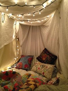 a bed covered in pillows and lights under a canopy