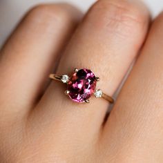 a woman's hand with a pink and white diamond ring on her left hand