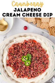 an overhead view of a cheese dip with jalapeno peppers on top and crackers in the background