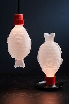 two white glass lamps sitting on top of a wooden table