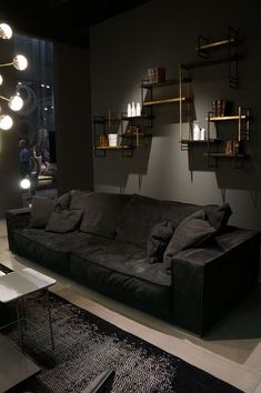 a living room filled with black furniture and lots of lights hanging from the wall above it