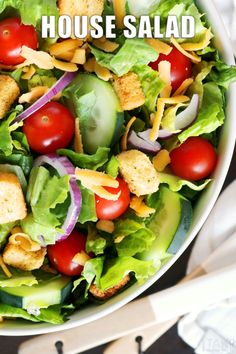 a salad with croutons, lettuce, tomatoes and cheese in it