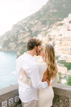 a man and woman standing next to each other near the ocean