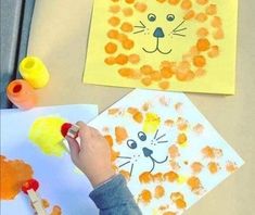 a child's hand holding a paintbrush and painting on paper with an animal