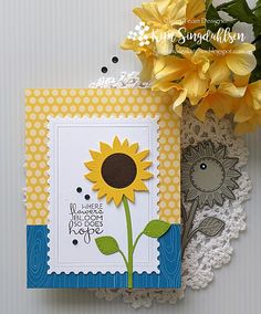 a card with a sunflower on it next to a doily and yellow flowers