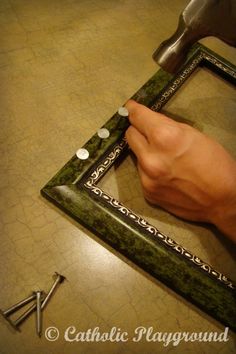 a person is using a hammer to cut through a green marble frame with screwdrivers