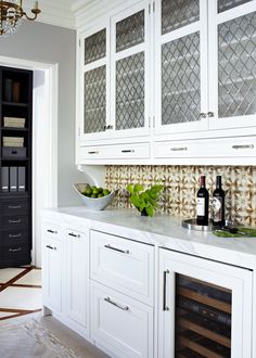 a kitchen with white cabinets and marble counter tops