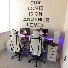 two computer desks sitting in front of a wall that says our love is on another level