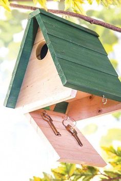 a bird house hanging from a tree branch with two keys attached to the top of it