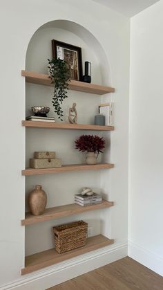 an arch in the wall is filled with books, vases and other decorative items