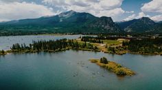 an aerial view of a lake with mountains in the background and canoes on the water