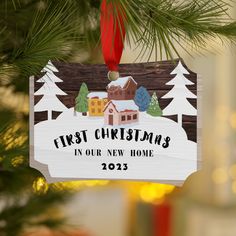 a wooden ornament hanging from a christmas tree that says first christmas in our new home