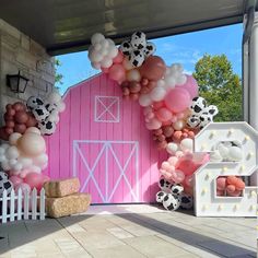 a pink barn decorated with balloons and farm animals