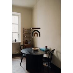 a black table with two chairs and a book on it in front of a window