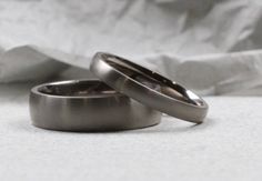 two wedding rings sitting next to each other on top of a white cloth covered bed