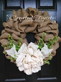 a burlock wreath with white flowers and green leaves on a black front door