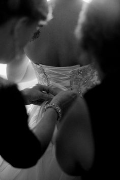 a woman in a wedding dress is fixing another woman's dress with her finger