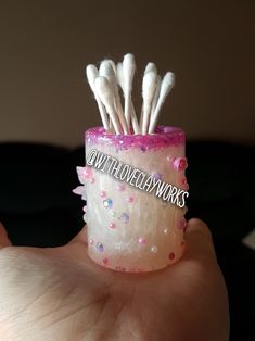 a hand holding a small cup with toothbrushes in it's top and bottom