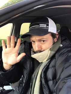 a man sitting in the back seat of a car holding his hand up to stop