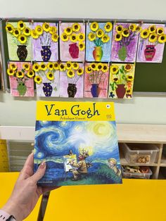 a person holding up a book about van gogh in front of a bunch of sunflowers