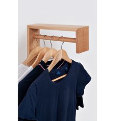 three shirts hanging on a wooden hanger in front of a wall mounted coat rack