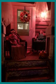 two people sitting on chairs in front of a door with halloween decorations hanging from the ceiling