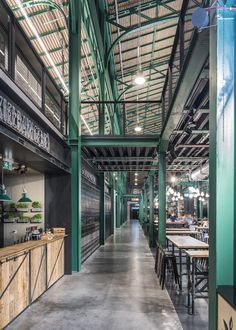 the inside of a building with tables and chairs in it's long hallway,