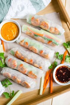 shrimp spring rolls with dipping sauce and carrots on a wooden platter, ready to be eaten